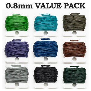 Könnte beinhalten: Ein Wertpaket mit neun Spulen 0,8 mm Kordel in verschiedenen Farben, darunter Grün, Türkis, Olive, Lila, Blau, Braun, Grau, Schwarz und Dunkelgrün. Der Text "0,8 mm VALUE PACK" steht oben.