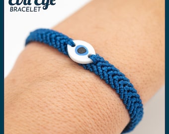 May include: A blue braided bracelet with a white evil eye charm. The charm has a blue eye and a black pupil.
