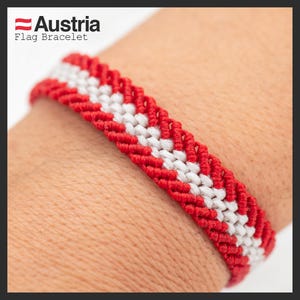 May include: Red and white braided bracelet with a chevron pattern, representing the Austrian flag. The bracelet is worn on a person's wrist. Austria Flag Bracelet.