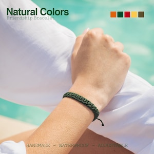 May include: A dark green friendship bracelet made of braided cord. The bracelet is adjustable and is shown on a person's wrist against a white background. The text "Natural Colors" and "Friendship Bracelet" is visible at the top of the image.