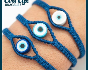 May include: Close-up of three blue Evil Eye bracelets. Each bracelet features a woven blue cord with a central eye-shaped bead. The beads have a blue, white, and black design. The text "Evil Eye BRACELET" is at the top.
