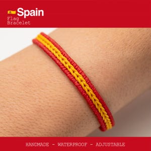 Puede incluir: Una pulsera hecha a mano, impermeable y ajustable con los colores de la bandera española: rojo y amarillo. La pulsera tiene un centro amarillo trenzado con bordes rojos. El texto "Spain Flag Bracelet" es visible.