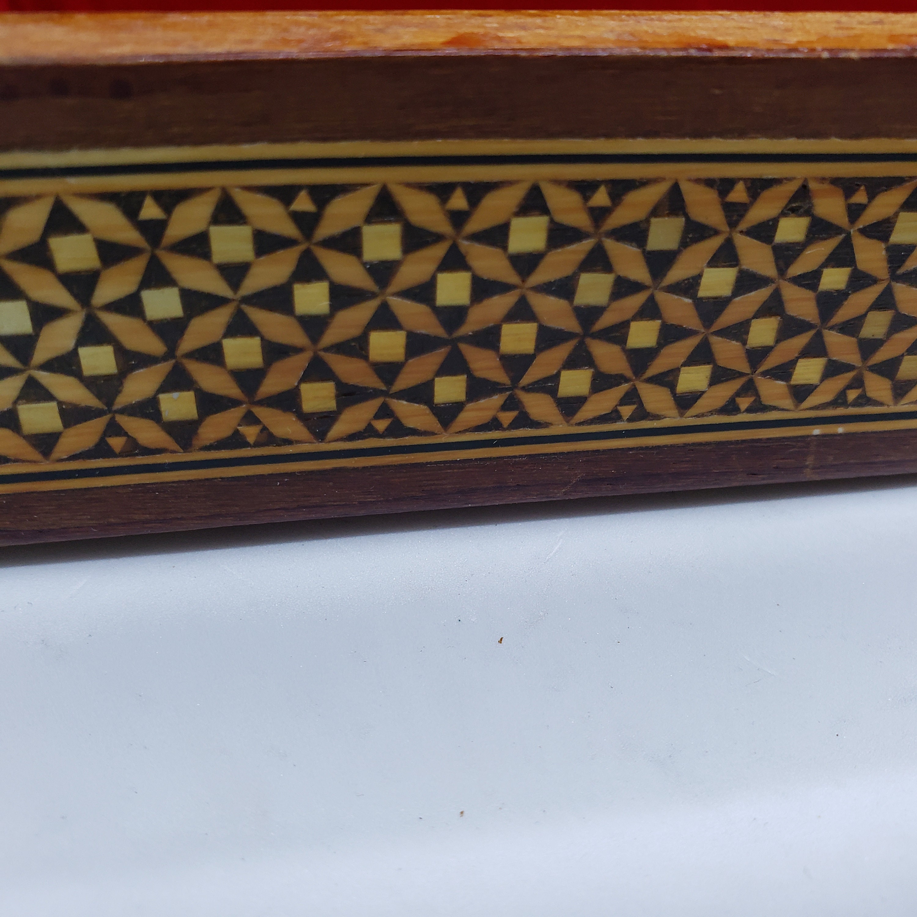 ヴィンテージの木製の蓋付き小物入れ。金と黒の幾何学模様。赤い