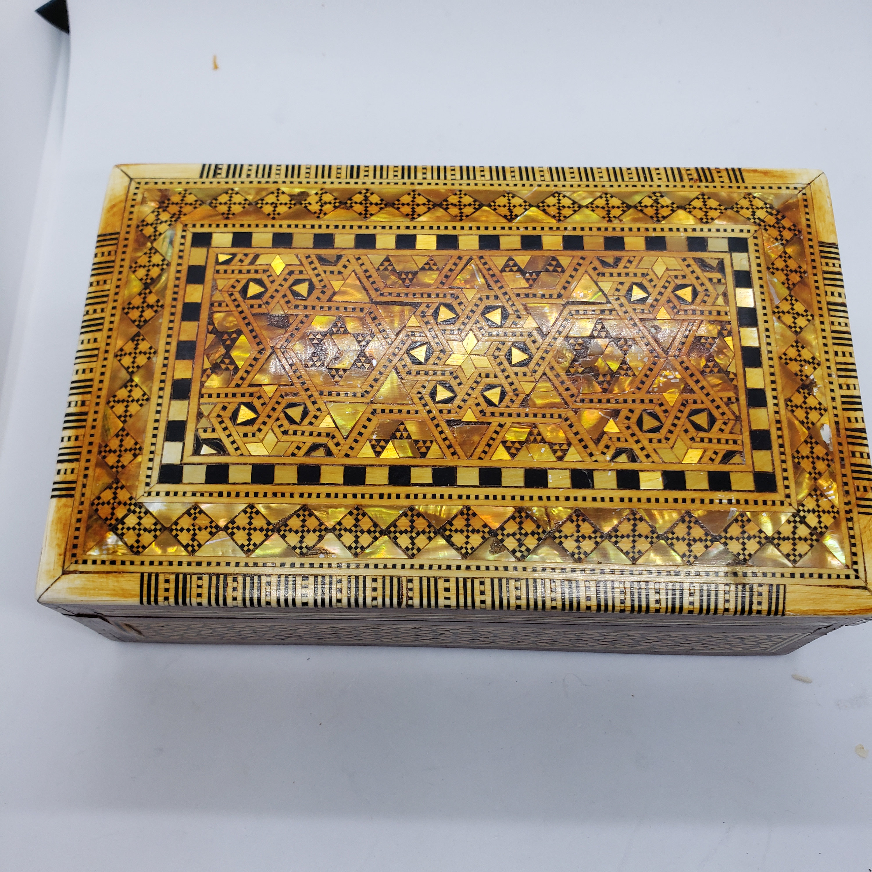 ヴィンテージの木製の蓋付き小物入れ。金と黒の幾何学模様。赤い