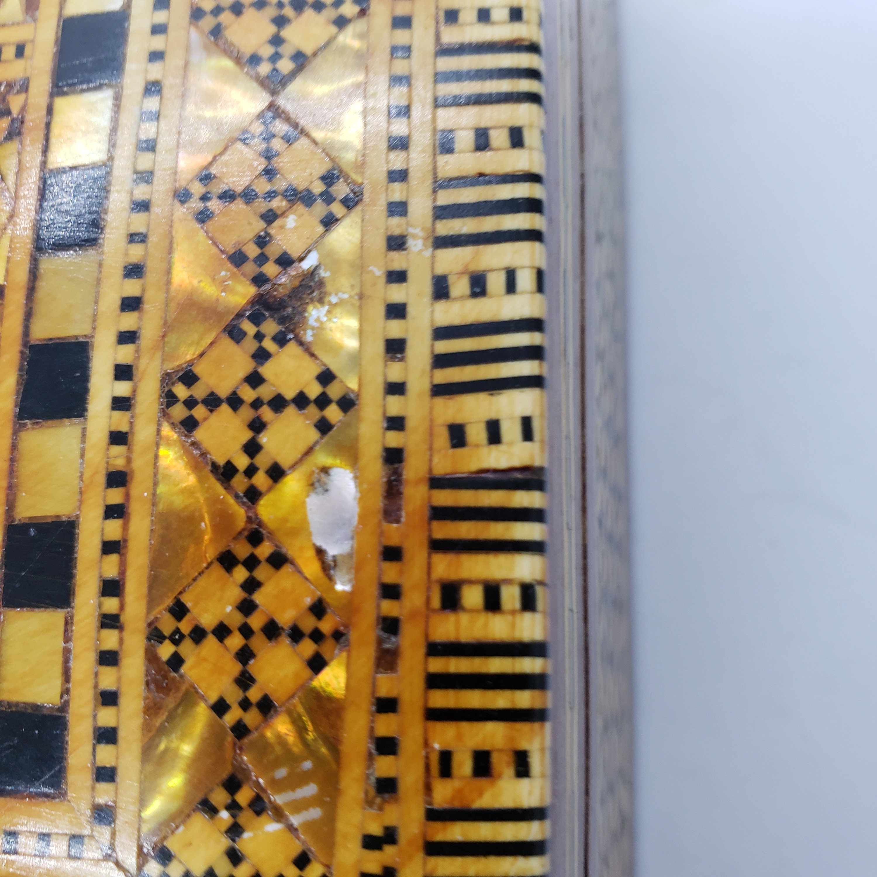 ヴィンテージの木製の蓋付き小物入れ。金と黒の幾何学模様。赤い