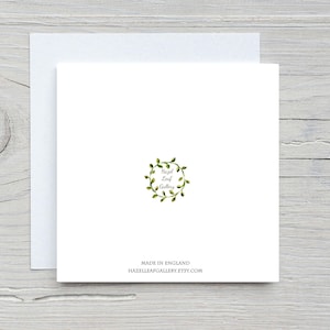 May include: A white square greeting card with a matching envelope. The card features a green wreath design with the text "Hazel Leaf Gallery". Below the design, it reads "Made in England" and the Etsy shop URL.