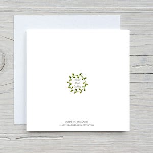 May include: A white square greeting card with a matching envelope. The card features a green wreath design with the text "Hazel Leaf Gallery." Below the design, it reads "Made in England" and the Etsy shop URL.