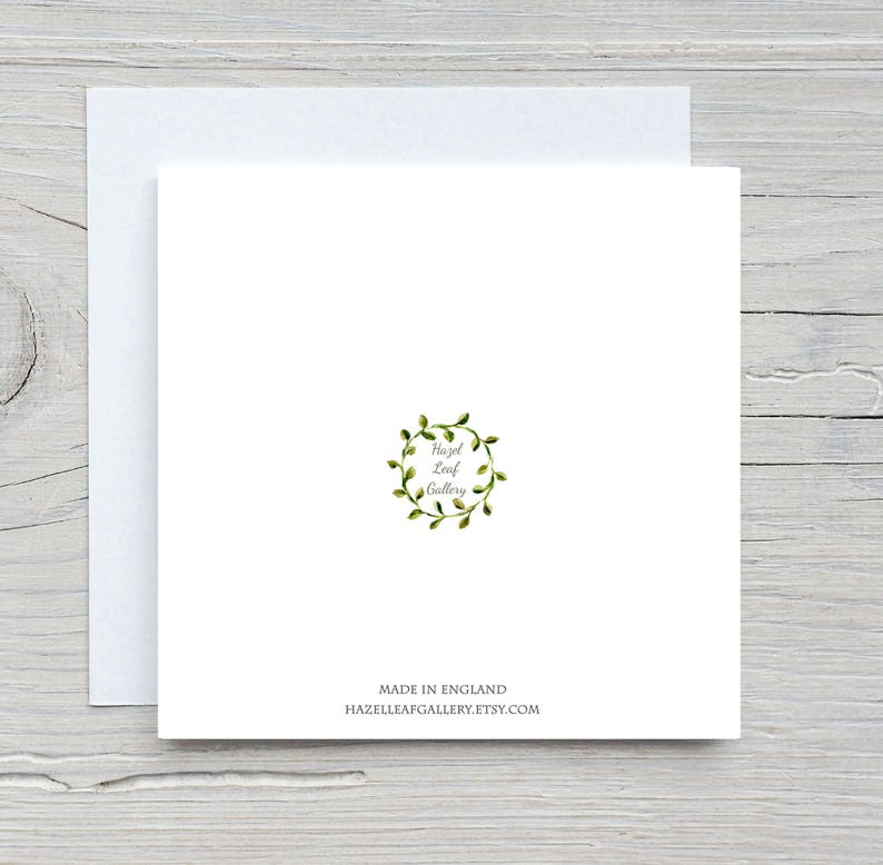 May include: A white square greeting card with a matching envelope. The card features a green wreath design with the text "Hazel Leaf Gallery." Below the design, it reads "Made in England" and the Etsy shop URL.