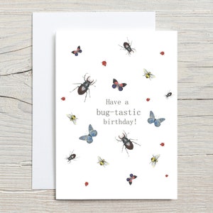 Peut inclure: Carte de v&oelig;ux blanche avec une enveloppe assortie. Elle pr&eacute;sente des illustrations &agrave; l'aquarelle d'insectes vari&eacute;s, tels que des col&eacute;opt&egrave;res, des papillons et des abeilles. Le texte "Have a bug-tastic birthday!" est imprim&eacute;.