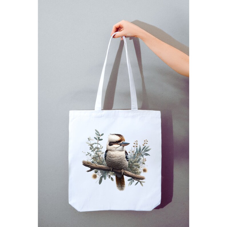 May include: White canvas tote bag featuring a colourful illustration of a kookaburra bird perched on a branch with green leaves and flowers.