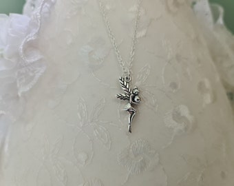May include: A silver necklace with a fairy charm holding a small orb. The charm is detailed and intricate, with delicate wings and a flowing dress. The necklace is on a white background.