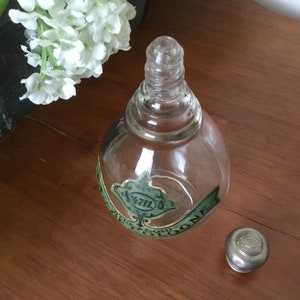 May include: A clear glass bottle with a green label that reads "4711" and "EAU DE COLOGNE". The bottle has a silver cap.