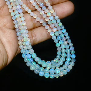 May include: A strand of iridescent white opal beads, strung on a silver chain. The beads are round and have a smooth, polished finish.