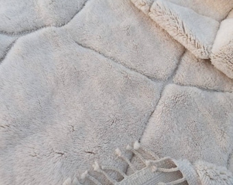 May include: A soft, fluffy, off-white rug with a geometric pattern. The rug has a textured, woven look and is made of a plush material.