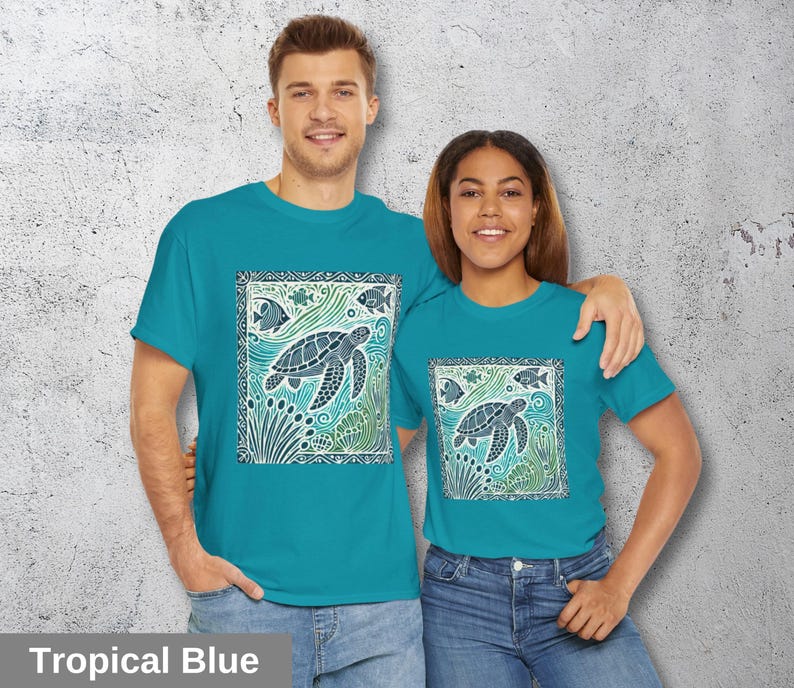 K&ouml;nnte beinhalten: Zwei Personen tragen t&uuml;rkisfarbene T-Shirts mit einem grafischen Design einer Meeresschildkr&ouml;te und Fischen in einem quadratischen Rahmen. Der Text "Tropical Blue" befindet sich am unteren Rand des Bildes.