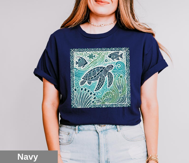 K&ouml;nnte beinhalten: Ein marineblaues T-Shirt mit einem grafischen Aufdruck einer Meeresschildkr&ouml;te, die in einem Korallenriff schwimmt. Das Design ist in einer Farbpalette aus Gr&uuml;n, Blau und Wei&szlig; gehalten.