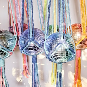 May include: A set of five rainbow macrame hanging planters with disco ball ornaments. Each planter has a tassel made of the same colour yarn as the macrame.