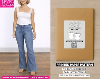Può includere: Una donna indossa un top bianco con spalline in tulle e jeans blu. È visibile anche una busta di carta marrone con un'etichetta che recita "Shoulder Tie Tank Top Sewing Pattern". Il testo "Printed Paper Pattern" è visibile.