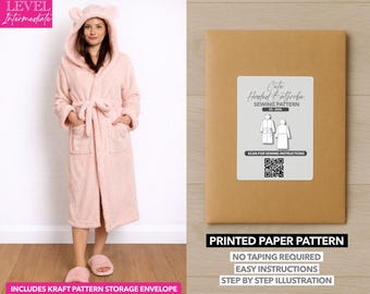 May include: A light pink hooded bathrobe with bear ears, a matching belt, and pockets. The image also shows a sewing pattern envelope with the text "Cute Hooded Bathrobe Sewing Pattern" and "Printed Paper Pattern". The pattern includes easy instructions.