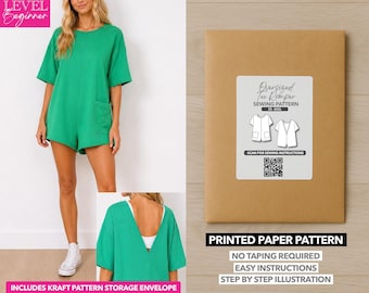 May include: A green short-sleeved romper with a front pocket and a deep V-back, shown with a brown kraft paper envelope labeled Oversized Tee Romper SEWING PATTERN XS-XXXL with a QR code for instructions and a printed paper pattern label.