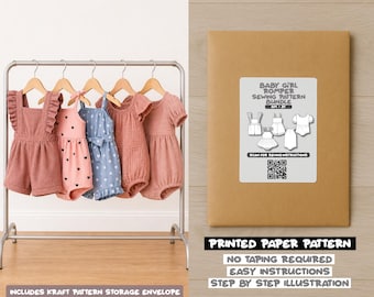 May include: A clothing rack displays five baby girl rompers in shades of pink and blue, with various designs. A kraft paper pattern bundle is on the right, with a label showing sewing pattern illustrations and text. The text at the bottom says "Printed Paper Pattern".