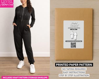 Può includere: Tuta nera con cappuccio, chiusura a zip e tasche. L'immagine mostra anche una busta di carta kraft con un'etichetta che recita "Hooded Jumpsuit Sewing Pattern". Il modello include istruzioni facili e illustrazioni passo passo.