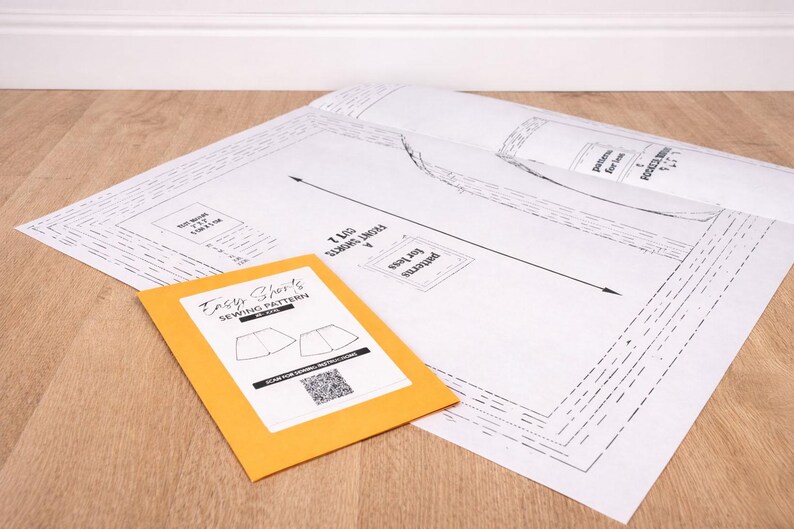 Easy Shorts Paper Sewing Pattern on a wooden workbench with manila envelop.