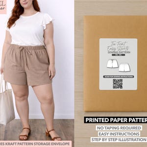 May include: A woman wearing a white top and brown shorts, holding a tote bag. Next to her is a brown paper pattern envelope with a label that reads "Tie Front Easy Shorts Sewing Pattern." The text "Printed Paper Pattern" is also visible.