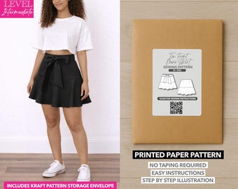 Può includere: Una donna indossa un top bianco corto e una minigonna nera con fiocco. L'immagine mostra anche una busta di carta modello marrone con un'etichetta che recita "Tie Front Mini Skirt Sewing Pattern". Il testo sulla busta dice anche "Printed Paper Pattern".