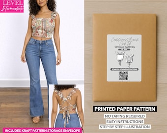 Può includere: Una donna indossa un top corto con stampa paisley e jeans blu. Viene mostrata anche una busta di carta kraft con un'etichetta per il modello di cucito. L'etichetta recita "Crisscross Back Crop Top Sewing Pattern".