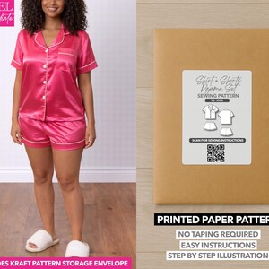 May include: A woman wearing a pink satin pajama set with white trim. The set includes a button-down shirt and shorts. Next to the woman is a brown paper pattern envelope with a label that reads "Shirt + Shorts Pajama Set Sewing Pattern". The text "Printed Paper Pattern" is also visible.