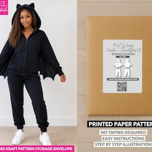 May include: A black zip-up hoodie with cat ears on the hood and bat-wing sleeves, paired with matching black sweatpants. Beside it is a brown kraft envelope with a label reading Bat Wings Hoodie + Sweatpants SEWING PATTERN XS-XXXL.