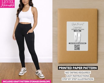Op de afbeelding: Een vrouw draagt ​​zwarte leggings met zijzakken en een witte sportbeha. Een bruine papieren patroon envelop met een wit label met de tekst "Side Pocket Leggings Sewing Pattern" wordt weergegeven. De tekst "Printed Paper Pattern" is ook zichtbaar.