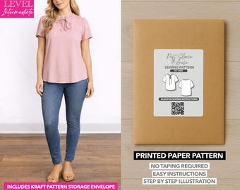 Può includere: Una donna indossa una camicetta rosa e jeans blu. Accanto a lei, una busta di carta marrone con un'etichetta bianca che recita "Puff Sleeve Blouse Sewing Pattern". La busta indica anche "Printed Paper Pattern" e "No Taping Required".