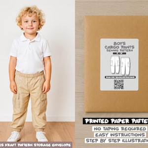May include: A young boy wearing a white polo shirt and khaki cargo pants stands next to a brown paper pattern envelope. The envelope has a label that reads "Boys Cargo Pants Sewing Pattern". The text "Printed Paper Pattern" is also visible.