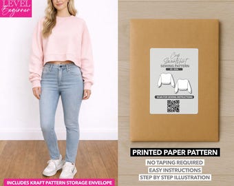 May include: A woman wearing a light pink cropped sweatshirt and light blue jeans. A brown paper package with a white label that reads "Crop Sweatshirt Sewing Pattern" is on the right. The package includes a kraft pattern storage envelope.