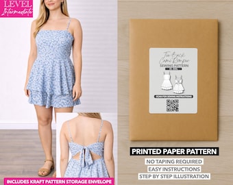 Può includere: Un prendisole cami con stampa floreale blu chiaro con spalline sottili e una gonna a balze. L'immagine mostra anche una busta di carta kraft con il testo "Tie Back Cami Romper Sewing Pattern". Il modello include istruzioni facili.