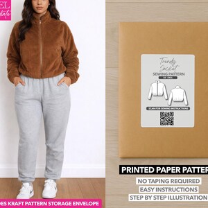 May include: A woman wearing a brown zip-up jacket and gray sweatpants. Next to her is a brown paper pattern envelope with a white label that reads "Trendy Jacket Sewing Pattern." The pattern includes a QR code and the text "Printed Paper Pattern."