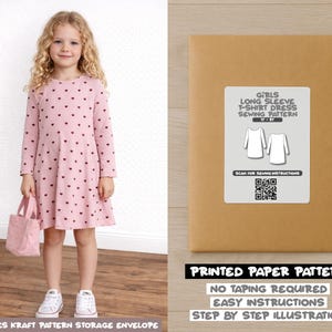 Op de afbeelding: Een jong meisje draagt een roze jurk met lange mouwen en een hartjespatroon, met een roze draagtas. Naast haar een bruine papieren patroon-envelop met de tekst "Girls Long Sleeve T-Shirt Dress Sewing Pattern".
