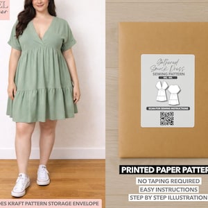 Op de afbeelding: Een vrouw draagt een saliegroene smockjurk met V-hals en gerimpelde rok, gecombineerd met witte sneakers. Naast haar een bruine papieren patroon envelop met het label "Gathered Smock Dress Sewing Pattern".