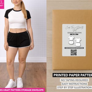 May include: A woman wearing a black and white crop top and black shorts with white trim. A brown paper pattern envelope with a label that reads "Crop Tee + Shorts Set Sewing Pattern" is next to her. The envelope also says "Printed Paper Pattern".