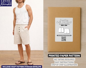 May include: A man wearing a white tank top and beige shorts with a drawstring and button closure. A brown paper package with a label that reads "Drawstring Button Front Shorts Sewing Pattern" is on the right. The package also says "Printed Paper Pattern".