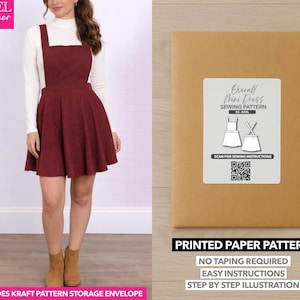 Puede incluir: Se muestra un minivestido con peto burdeos con falda acampanada. El vestido se combina con un cuello alto blanco y botas marrones. También se muestra un sobre de papel kraft con una etiqueta de patrón de costura.