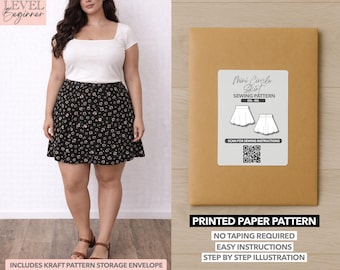 May include: A woman wearing a white square-neck top and a black floral print mini skirt. Next to her is a brown paper pattern envelope with a label that reads "Mini Circle Skirt Sewing Pattern". The envelope also states "Printed Paper Pattern".