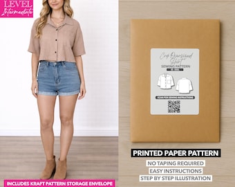 May include: A woman wearing a tan cropped shirt and denim shorts. A brown paper envelope with a white label that reads "Crop Oversized Shirt Sewing Pattern" is next to her. The envelope also says "Printed Paper Pattern" and "Includes Kraft Pattern Storage Envelope."