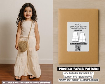 Op de afbeelding: Een jong meisje draagt een crèmekleurige outfit en een ronde geweven tas. Naast haar ligt een bruine papieren envelop met het opschrift "GIRLS SUMMER PANTS SEWING PATTERN". De envelop vermeldt ook "PRINTED PAPER PATTERN" en "NO TAPING REQUIRED".
