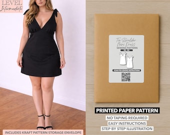 May include: A black mini dress with tie shoulder straps and a V-neck. The dress is worn by a person. Next to the person is a brown paper pattern envelope with a white label that reads "Tie Shoulder Mini Dress Sewing Pattern". The envelope also says "Printed Paper Pattern".