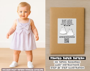 May include: A baby girl wearing a light purple and white striped dress with a large bow on the front. The dress has thin straps and a flared skirt. Next to the baby is a brown paper envelope with a label that reads "Baby Girls Bow Front Cami Dress Sewing Pattern."