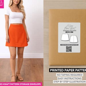 Op de afbeelding: Een vrouw draagt een witte crop top en een oranje A-lijn minirok. Naast haar staat een bruine papieren patroon envelop met het opschrift "A-lijn Minirok Naaipatroon". De envelop vermeldt ook "Gedrukt Papieren Patroon".