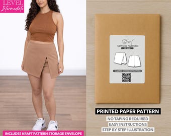 Op de afbeelding: Een vrouw draagt een bruine crop top en een tan skort. De afbeelding toont ook een gedrukt papieren patroon voor een skort, met de tekst "Skort Sewing Pattern" en "Printed Paper Pattern". Het patroon bevat een kraft patroon opberg envelop.